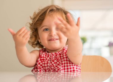 Evde dikkat isteyen tutmak için soran gülümseyen güzel sarışın çocuk.