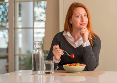 Kızıl saçlı kadın yeme meyve tabağı, kivi ve çilek, soru, çok karışık fikir hakkında ciddi bir yüz düşünme Anasayfa