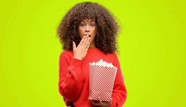 Mujer Afroamericana Comiendo Palomitas Maíz Cubrir Boca Con Mano Conmocionada —  Fotos de Stock