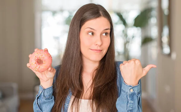 Mulher Nova Com Fome Segurando Donut Rosa Apontando Com Mão — Fotografia de Stock