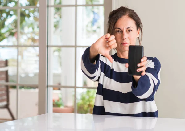 中年妇女使用智能手机与愤怒的脸 消极的迹象显示不喜欢拇指下降 拒绝概念 — 图库照片