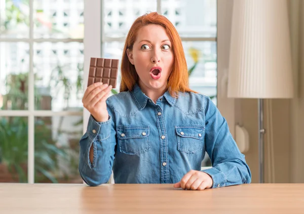 Mulher Ruiva Segurando Barra Chocolate Casa Assustada Choque Com Rosto — Fotografia de Stock