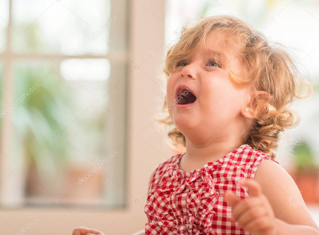 Beautiful blond child crying and shouting with tantrum at home.