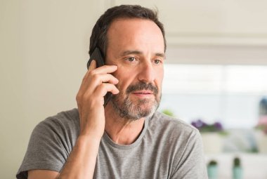 Acımak yüz ciddi düşünüyorum üstünde kendine güvenen bir ifade ile akıllı telefon kullanan orta yaş adam