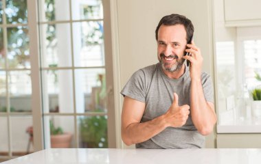 Ok işareti, başparmak ile parmak, mükemmel işareti yapıyor kocaman bir gülümseme ile Smartphone mutlu kullanan orta yaş adam