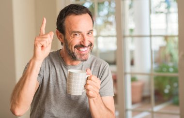 Gülen yüz, bir numara ile bir fikir ya da soru işaret parmağı ile orta yaş erkek bir fincan kahve içme şaşırttı