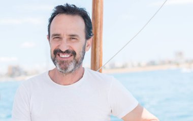 Yelkenli üzerinde seyahat ve mutlu ve kendinden emin gülümseyen kıdemli yakışıklı