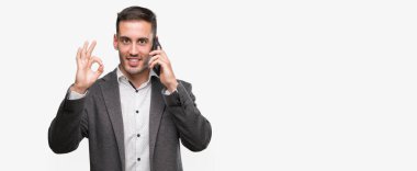 Parmak, mükemmel sembolü ile ok işareti yapıyor smartphone kullanarak yakışıklı genç