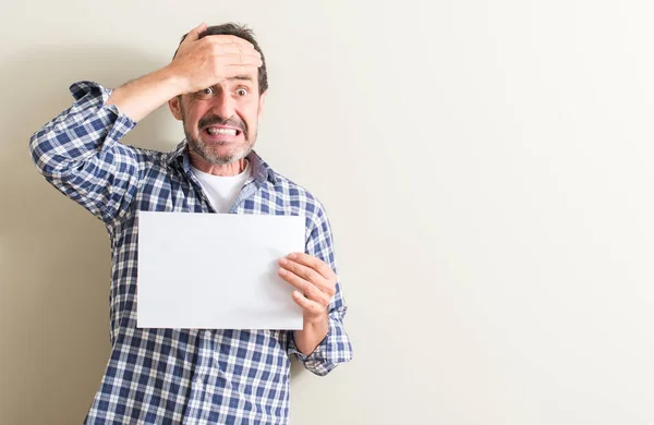 Homem Sênior Segurando Folha Papel Branco Estressado Com Mão Cabeça — Fotografia de Stock