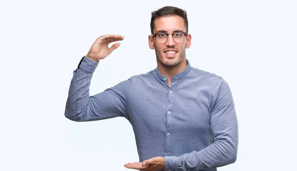 ハンサムな若いエレガントな男は眼鏡をかけてメジャー シンボル兆し大きな 大きなサイズの手でジェスチャーします カメラを見て笑っています 測定概念 — ストック写真