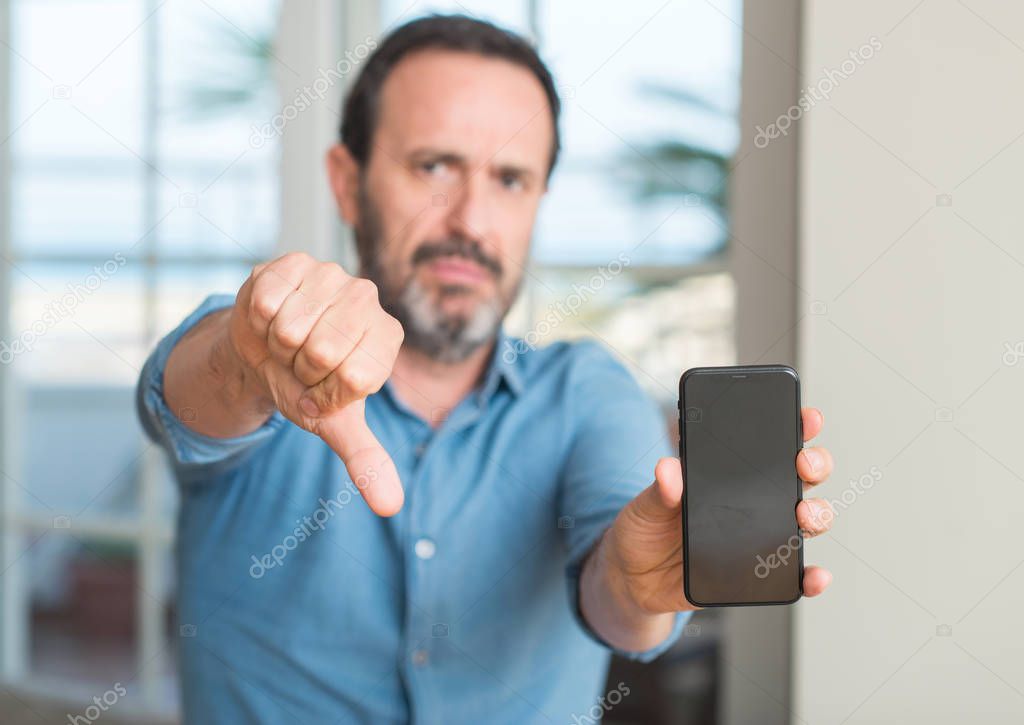 Middle age man using smartphone with angry face, negative sign showing dislike with thumbs down, rejection concept