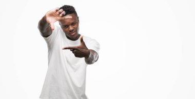 Elle yapma çerçeve ve parmakları ile mutlu yüz gülümseyen beyaz t-shirt giyen genç Afro-Amerikan adam. Yaratıcılık ve Fotoğrafçılık kavramı.