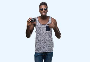 Afro-Amerikan delikanlı kendisine sürpriz yüz işaret parmağı Vintage kamera tutarak