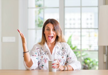 Genç kadın evde kahve çok mutlu ve heyecanlı, kazanan ifade büyük gülümseme ile çığlık zaferini kutluyor içme ve ellerini kaldırdı