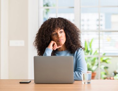 Dizüstü bilgisayar kullanan çok ev ciddi yüz düşünme soru hakkında Afrikalı-Amerikalı kadın fikir karışık