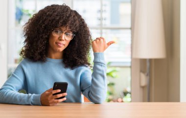 El ve parmak ile yukarı dönük mutlu yüz gülümseyen ile smartphone kullanarak güzel bir Afrikalı-Amerikalı kadın