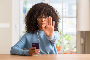 Açık eliyle dur işareti ile ciddi ve kendine güvenen ifade, savunma jest yapıyor Smartphone kullanarak güzel bir Afrikalı-Amerikalı kadın