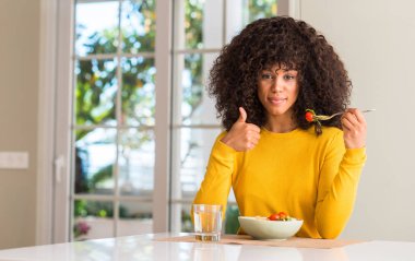 Afrikalı-Amerikalı kadın ok işareti, başparmak ile parmak, mükemmel işareti yapıyor kocaman bir gülümseme ile makarna salatası mutlu yemek