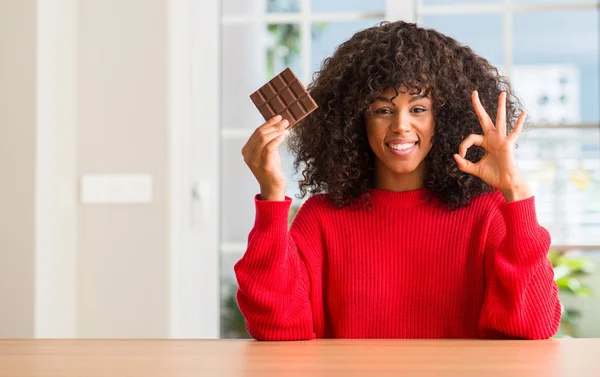 Africano Americano Mulher Comer Chocolate Bar Casa Fazendo Sinal Com — Fotografia de Stock