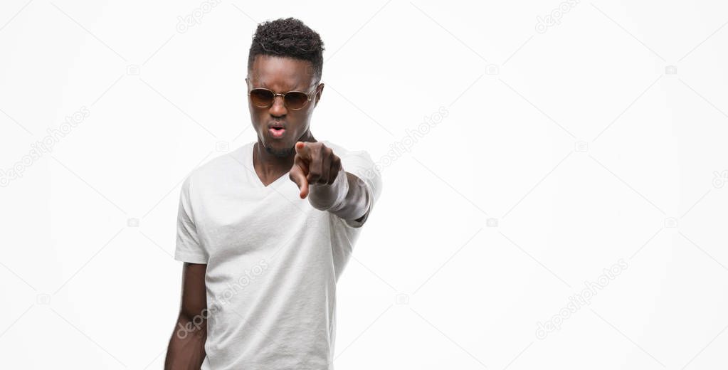 Young african american man wearing sunglasses pointing with finger to the camera and to you, hand sign, positive and confident gesture from the front