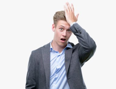 Young handsome blond business man surprised with hand on head for mistake, remember error. Forgot, bad memory concept. clipart