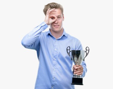 Genç yakışıklı sarışın adam bir kupa ile ok işareti ile el parmaklarının arasından seyir göze yapıyor gülümseyen mutlu yüz tutan