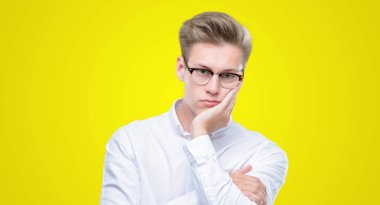 Genç yakışıklı sarışın adam düşünme seyir yorgun ve sıkılmış çapraz silah depresyon sorunları ile.