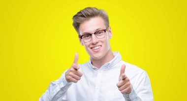 Parmak kamera ile mutlu ve komik yüz işaret eden genç yakışıklı sarışın adam. İyi enerji ve vibes.