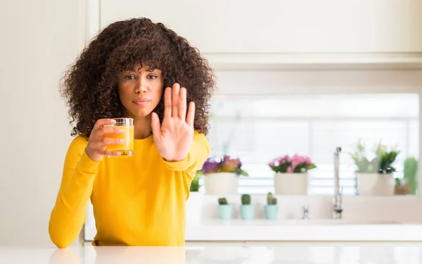 非洲裔美国人妇女喝橙汁在玻璃用张开手做停止标志以严肃和自信的表达 防御姿态 — 图库照片