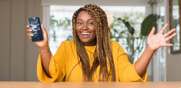 African american woman showing broken smartphone very happy and excited, winner expression celebrating victory screaming with big smile and raised hands