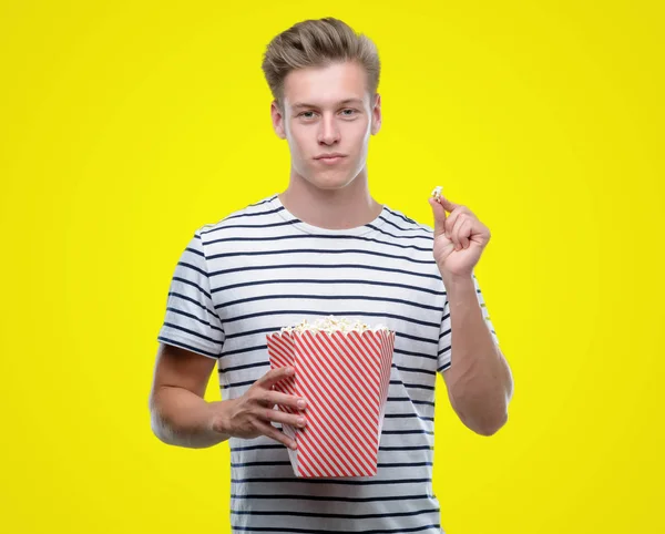 Junger Schöner Blonder Mann Der Popcorn Mit Selbstbewusstem Gesichtsausdruck Isst — Stockfoto