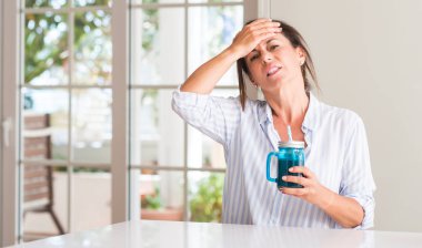 Orta yaşlı kadın elle kafasına, utanç ve sürpriz yüz ile şok vurguladı bir bardak muzlu süt içme öfkeli ve sinirli. Korku ve hata için üzgün.