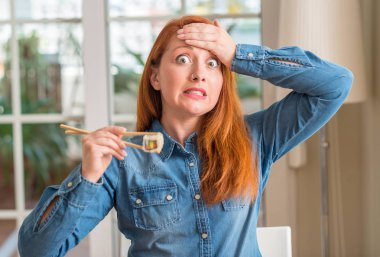 Kızıl saçlı kadının kafasına, el ile vurguladı yemek çubukları kullanarak suşi yemek şok utanç ve sürpriz suratla, öfkeli ve sinirli. Korku ve hata için üzgün.