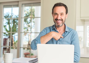 Orta yaş adam kendisi için sürpriz yüz işaret parmağı ile dizüstü evde kullanma