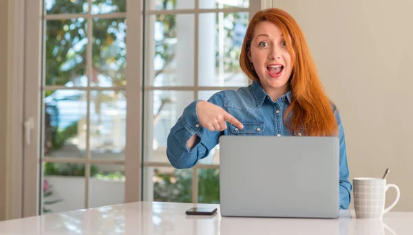 红发妇女使用电脑笔记本电脑在家里非常高兴地指着手和手指 — 图库照片