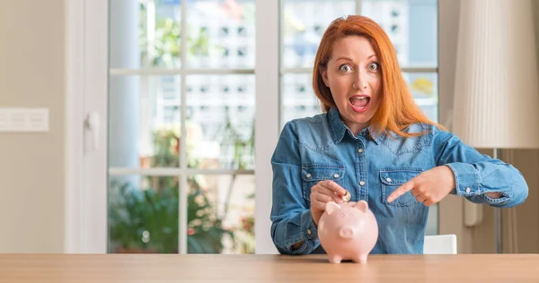 Redhead Woman Saves Money Piggy Bank Home Very Happy Pointing — Stock Photo, Image