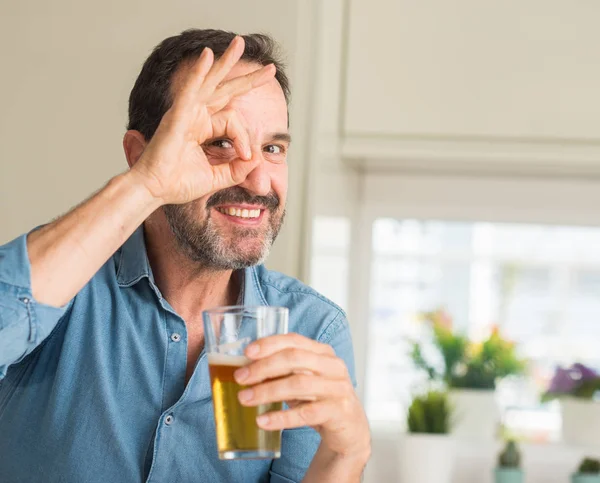 指の間から見て目に手で サインをして笑っている幸せそうな顔でビールを飲む中年男性 — ストック写真