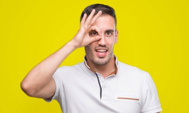 Mutlu yüz el parmaklarının arasından seyir göz üzerinde ok işaretiyle yapıyor gülümseyen ile beyaz t-shirt giyiyor rahat yakışıklı genç