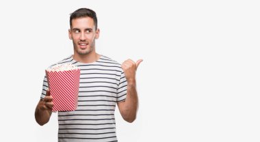 El ve parmak ile yukarı dönük mutlu yüz gülümseyen ile yakışıklı genç adam yeme patlamış mısır