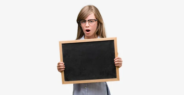 Young Blonde Child Holding Blackboard Scared Shock Surprise Face Afraid — Stock Photo, Image