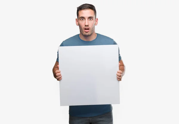 Handsome Young Man Holding Advertising Banner Scared Shock Surprise Face — Stock Photo, Image