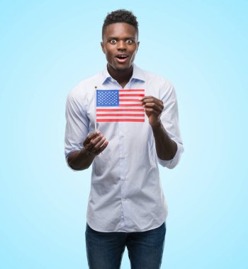 ABD bayrağı bir sürpriz yüz, korkuyor ve heyecanlı korku ifadesi ile şok korkmuş tutan genç Afro-Amerikan adam