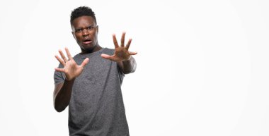 Korkuyor ve korku ifade dur hareketi el ile ile dehşete şokta bağırarak gri t-shirt giyen genç Afro-Amerikan adam. Panik kavramı.