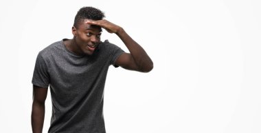 Çok mutlu ve gülümseyen uzakta el ile üzerine kafa seyir gri t-shirt giyen genç Afro-Amerikan adam. Arama kavramı.