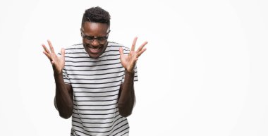 Gözlük ve lacivert t-shirt kaldırdı kollarını açarak kızgın ve başarı için deli kutluyor ve heyecanlı çığlık kapalı gözler giyen genç Afro-Amerikan adam. Kazanan kavramı