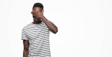 Gözlük ve gülümsüyor ve gözleri için sürpriz kapsayan yüz el ile gülüyor lacivert t-shirt giyen genç Afro-Amerikan adam. Kör kavramı.