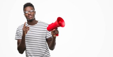 Genç Afro-Amerikan holding megafon bir fikirle şaşırmış adam ya da gülen yüz, bir numara ile işaret parmağı soru