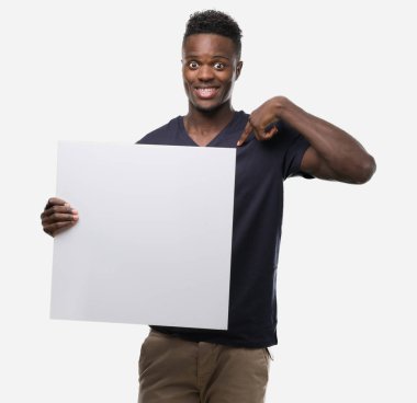 Sürpriz yüz işaret parmağı bir afiş için kendini tutan genç Afro-Amerikan adam