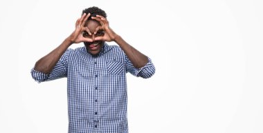 Dilini, parmaklarının arasından baktığını yapışmasını dürbün gibi ok jest yapıyor mavi gömlek giymiş genç Afro-Amerikan adam. Deli ifade.