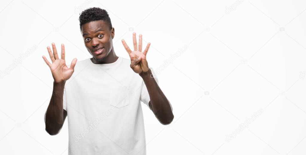 Young african american man wearing white t-shirt showing and pointing up with fingers number nine while smiling confident and happy.